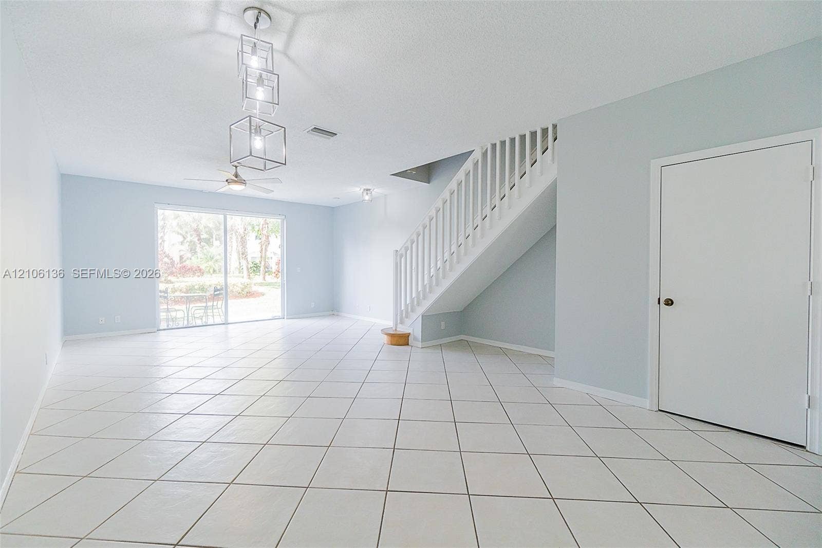 3713 San Simeon Circle, Weston, Weston, FL 33331 Open-concept interior featuring large-format ceramic tile flooring, a geometric multi-pendant light fixture, a ceiling fan, and a staircase with white vertical railings