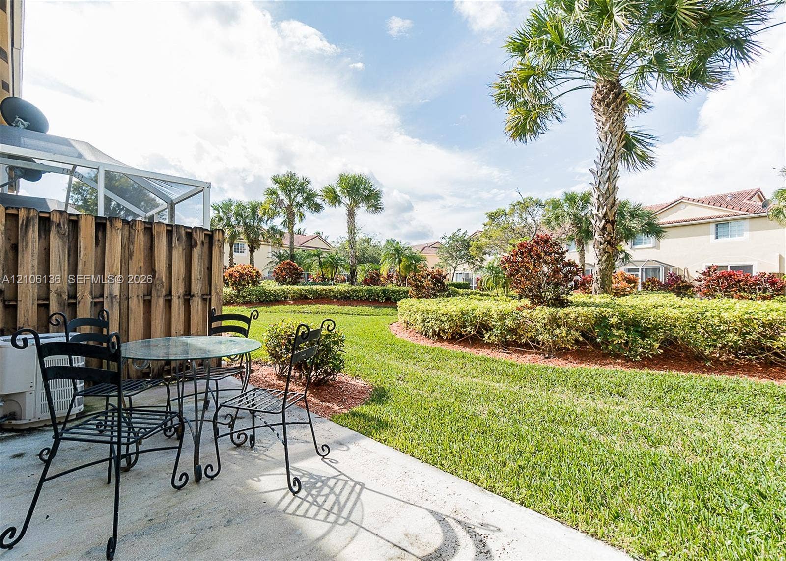 3713 San Simeon Circle, Weston, Weston, FL 33331 Concrete patio featuring a privacy fence, manicured lawn, established landscaping, and palm trees