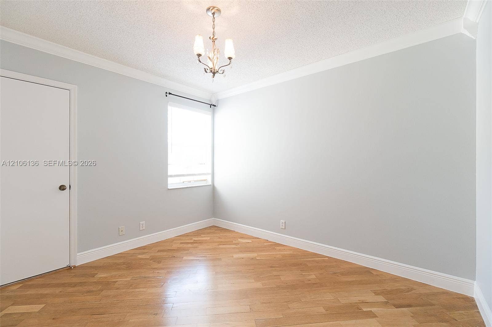 3713 San Simeon Circle, Weston, Weston, FL 33331 Bright corner bedroom with refinished wood-finish flooring, abundant natural light from large window, ceiling pendant fixture, and fresh white walls with crown molding detail