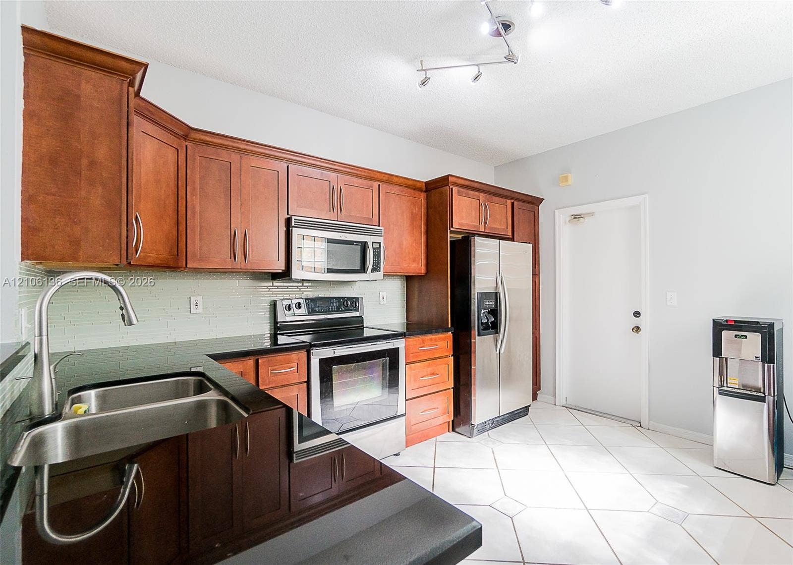 3713 San Simeon Circle, Weston, Weston, FL 33331 Kitchen featuring cherry-tone cabinetry, dark stone-finish countertops, stainless steel appliances, light-colored tile flooring, and track lighting