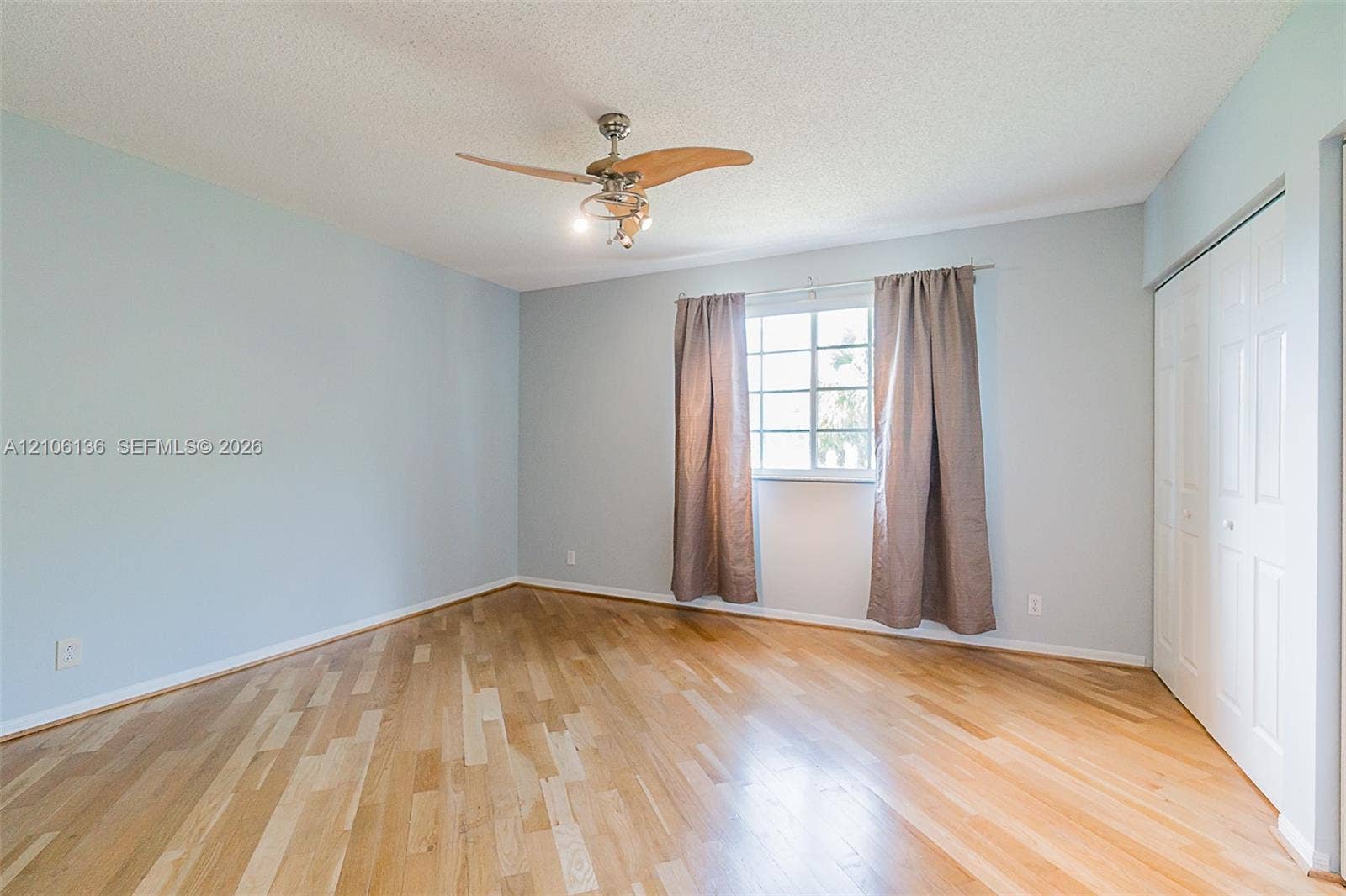 3713 San Simeon Circle, Weston, Weston, FL 33331 Light-filled interior featuring wood-finish flooring, a multi-pane window, a ceiling fan with integrated lighting, and a bi-fold closet