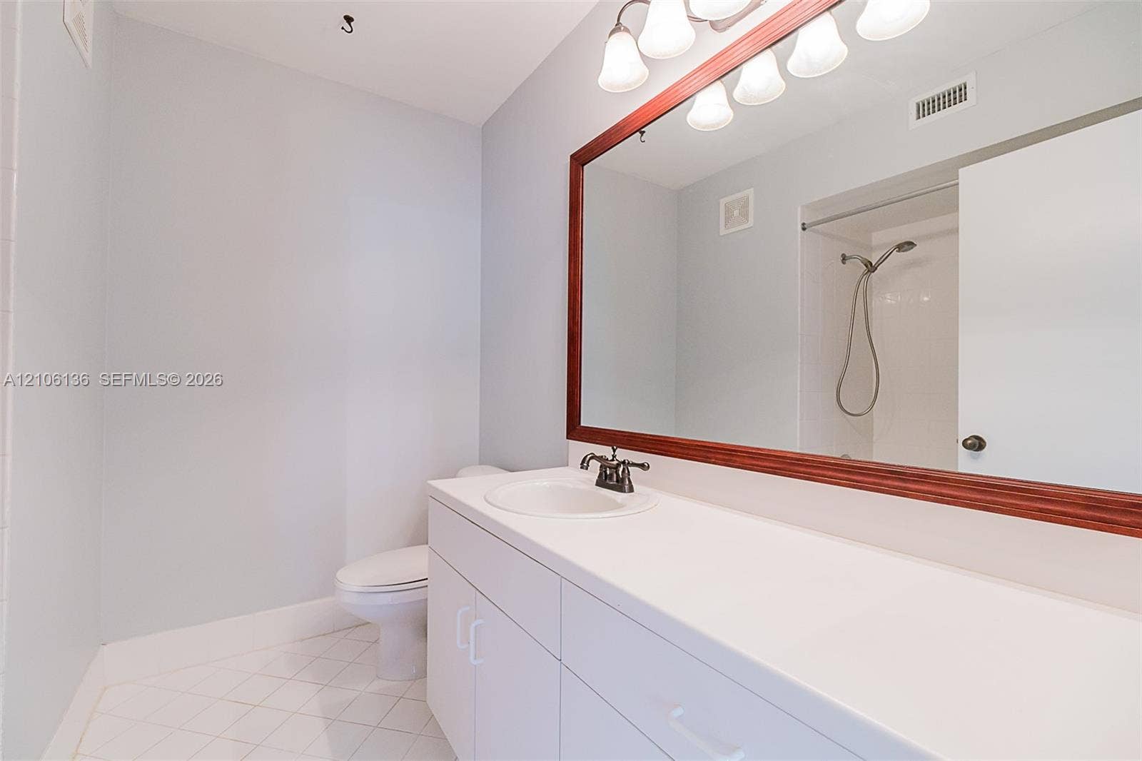 3713 San Simeon Circle, Weston, Weston, FL 33331 Bathroom featuring a white vanity with an integrated sink, a large wood-framed wall mirror, multi-bulb overhead lighting, and white tile flooring