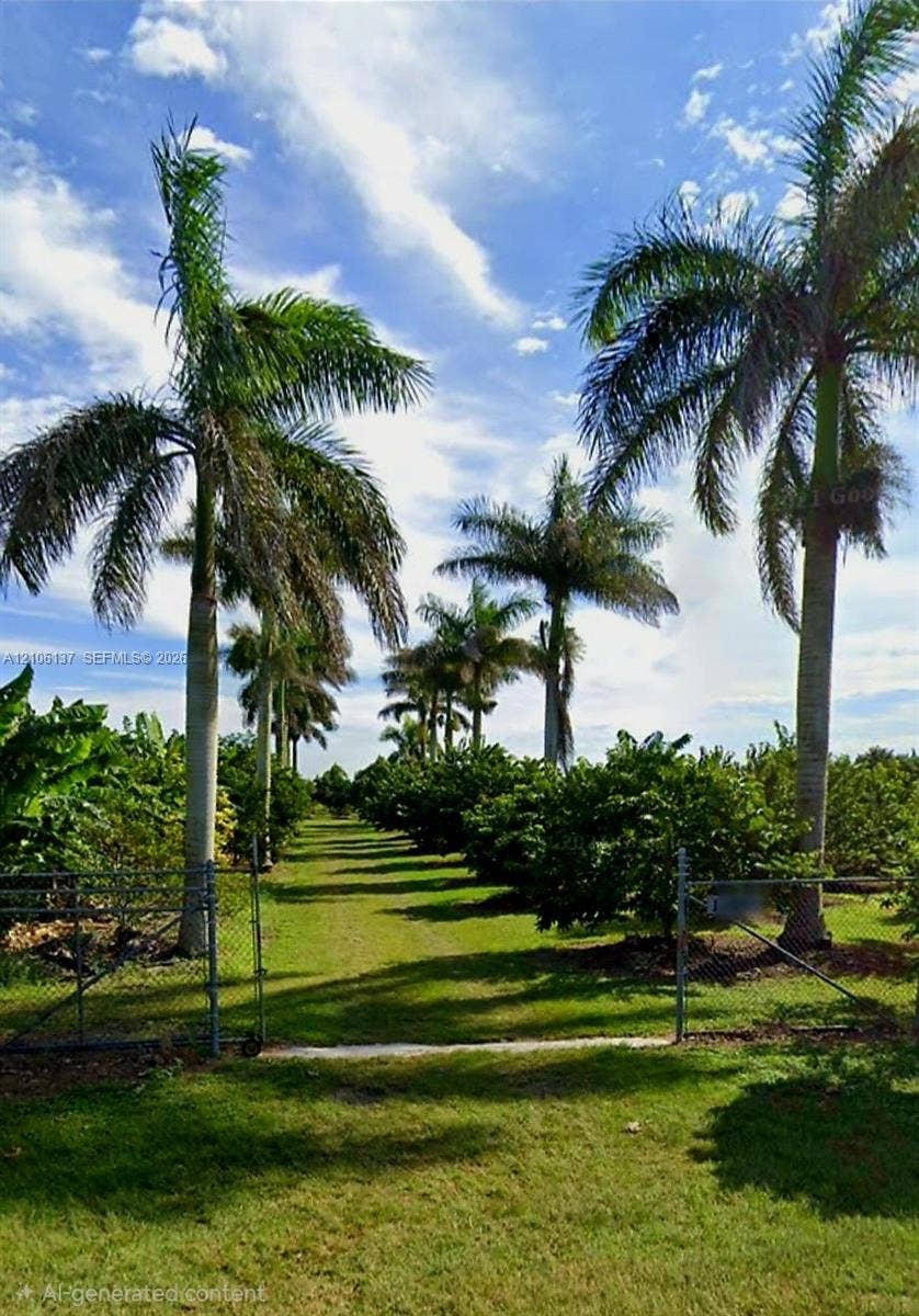 Expansive grounds featuring rows of mature palm trees, dense established vegetation, and chain-link perimeter fencing