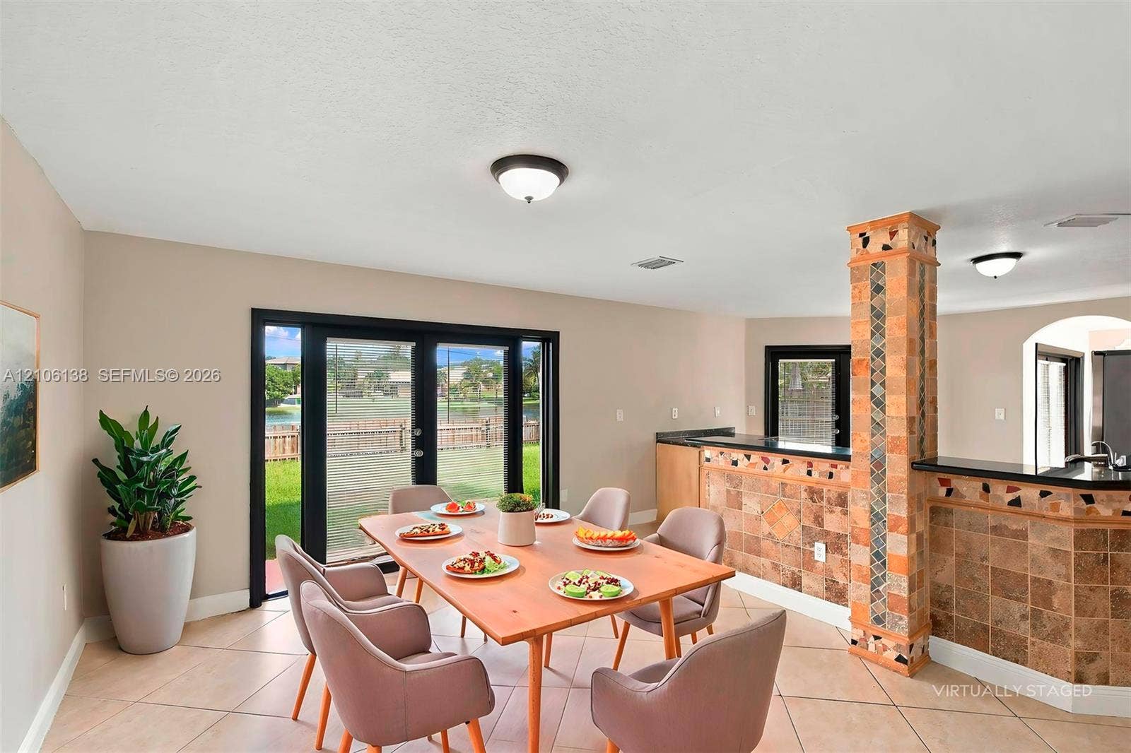 16119 SW 61st Lane, Miami, Miami, FL 33193 Open-concept space featuring tile flooring, natural stone-clad support pillar and matching bar, and double glass-paned doors with black frames