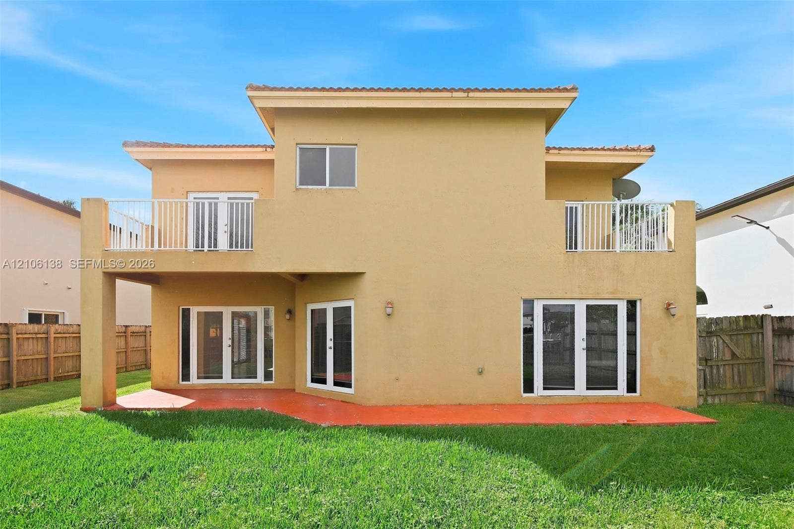 16119 SW 61st Lane, Miami, Miami, FL 33193 Two-story exterior featuring a stucco facade, covered patio, upper-level balcony with metal railing, and multiple sets of glass-paned doors