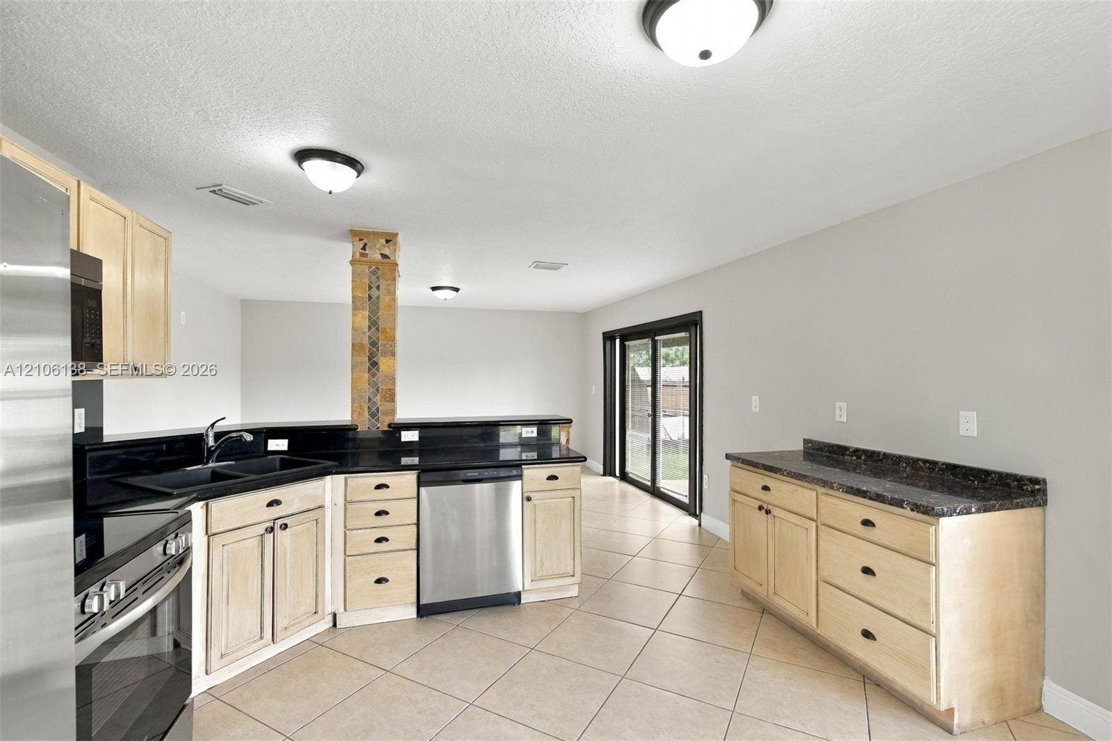 16119 SW 61st Lane, Miami, Miami, FL 33193 Kitchen featuring light wood-finish cabinetry, dark solid-surface countertops, built-in stainless steel appliances, a decorative tiled support pillar, and ceramic tile flooring