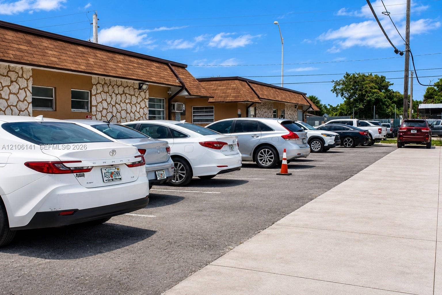 5190 E 10th Avenue, #1, Hialeah, Hialeah, FL 33013 Exterior facade featuring stone-veneer accents and shingled roofing, accompanied by a paved parking lot and concrete walkway