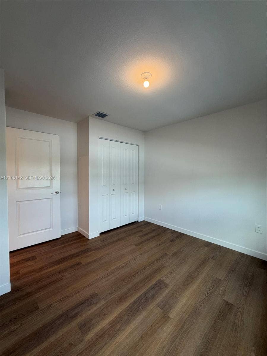 Interior space featuring wood-finish flooring, white panel doors, and a double-door closet