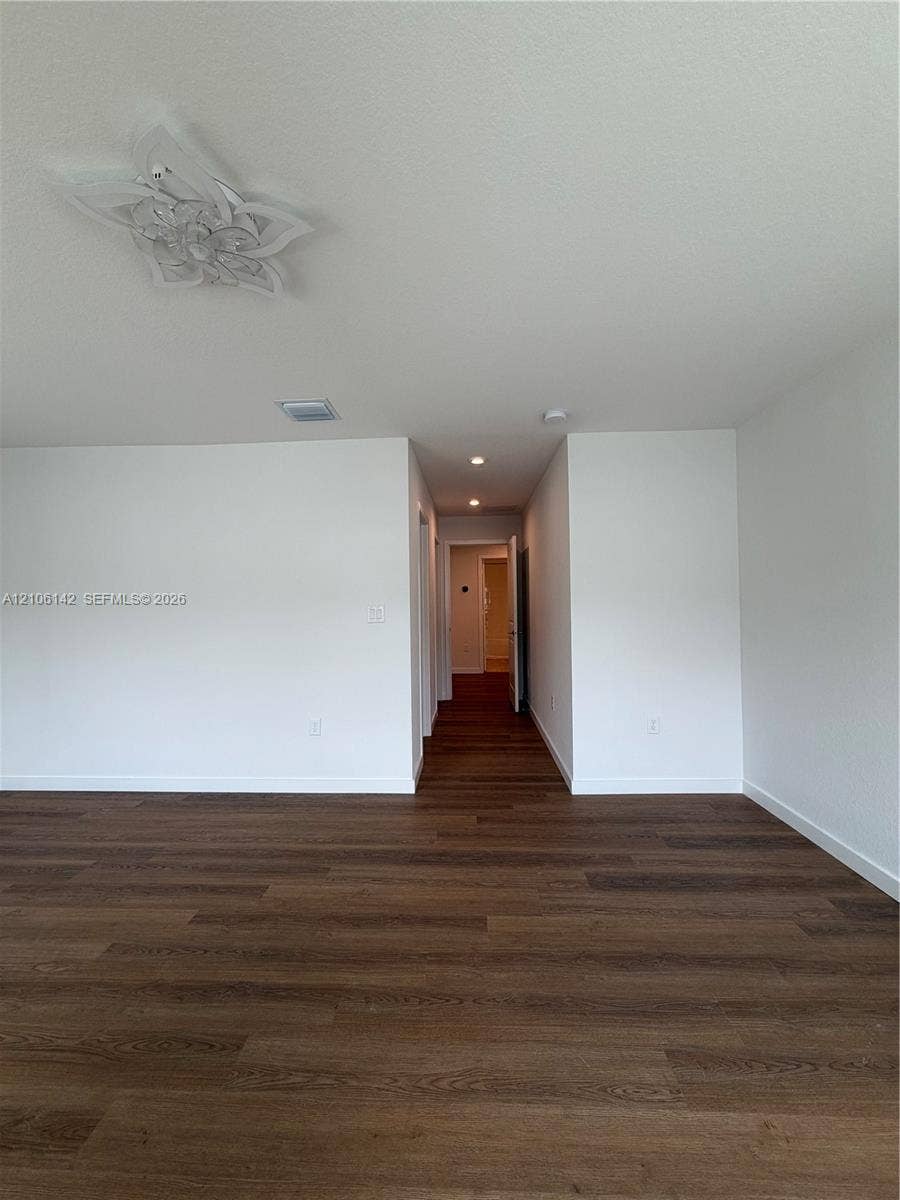 Interior space featuring wood-finish flooring, decorative ceiling-mounted light fixture, recessed lighting, and white walls