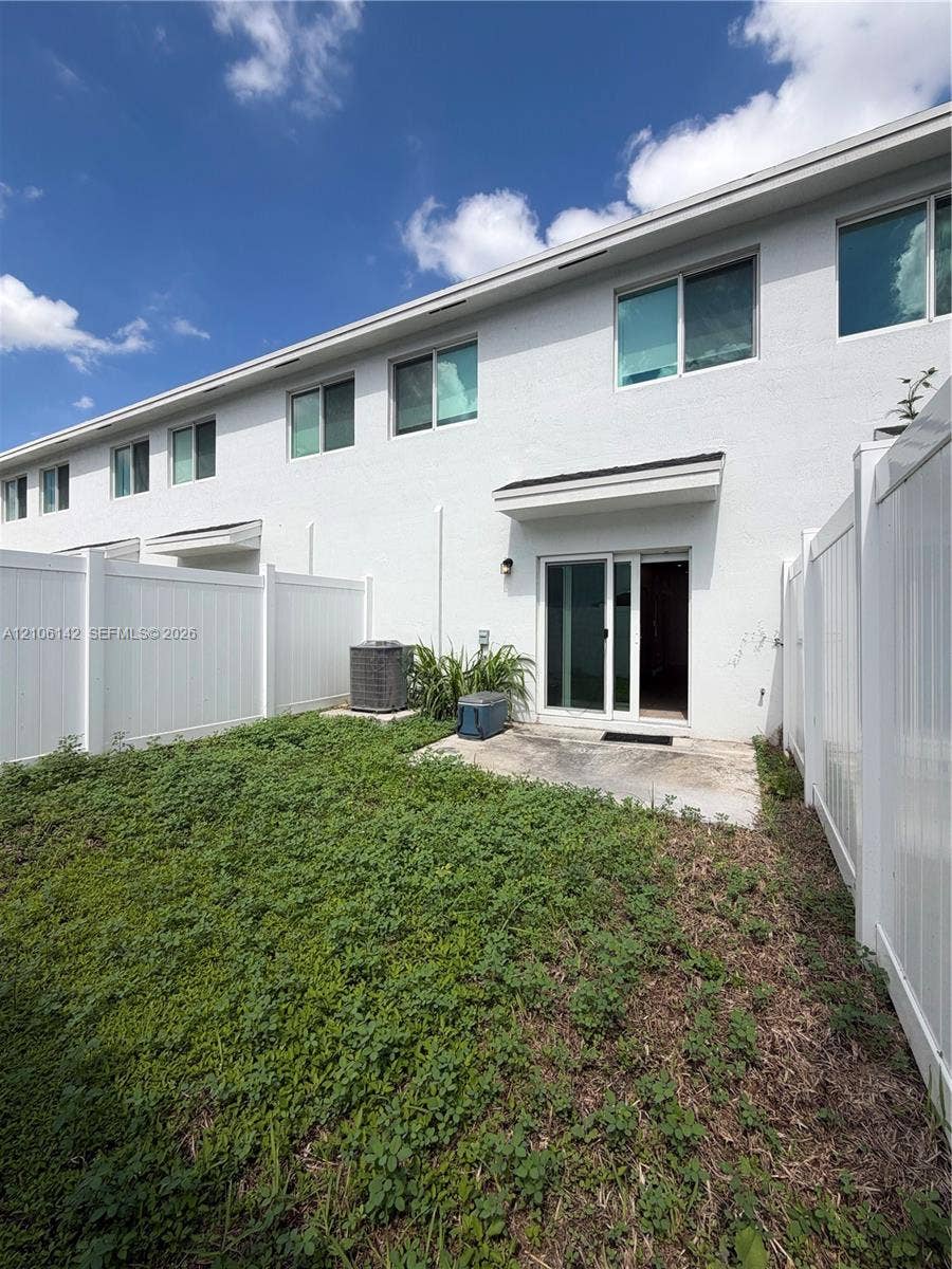 Fenced backyard featuring a concrete patio, sliding glass door entry, and white exterior finish