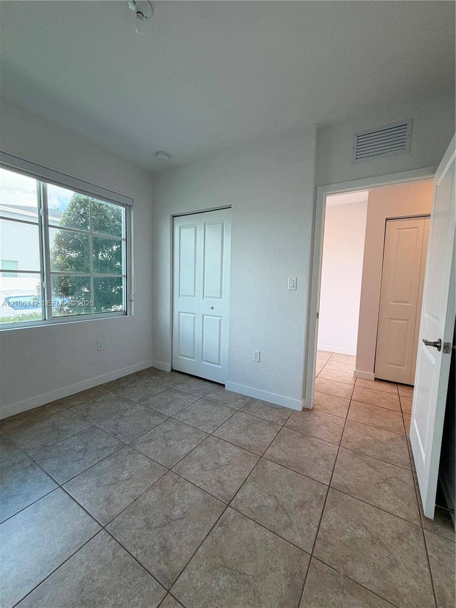 Neutral-toned ceramic tile flooring, multi-pane window, and interior paneled doors