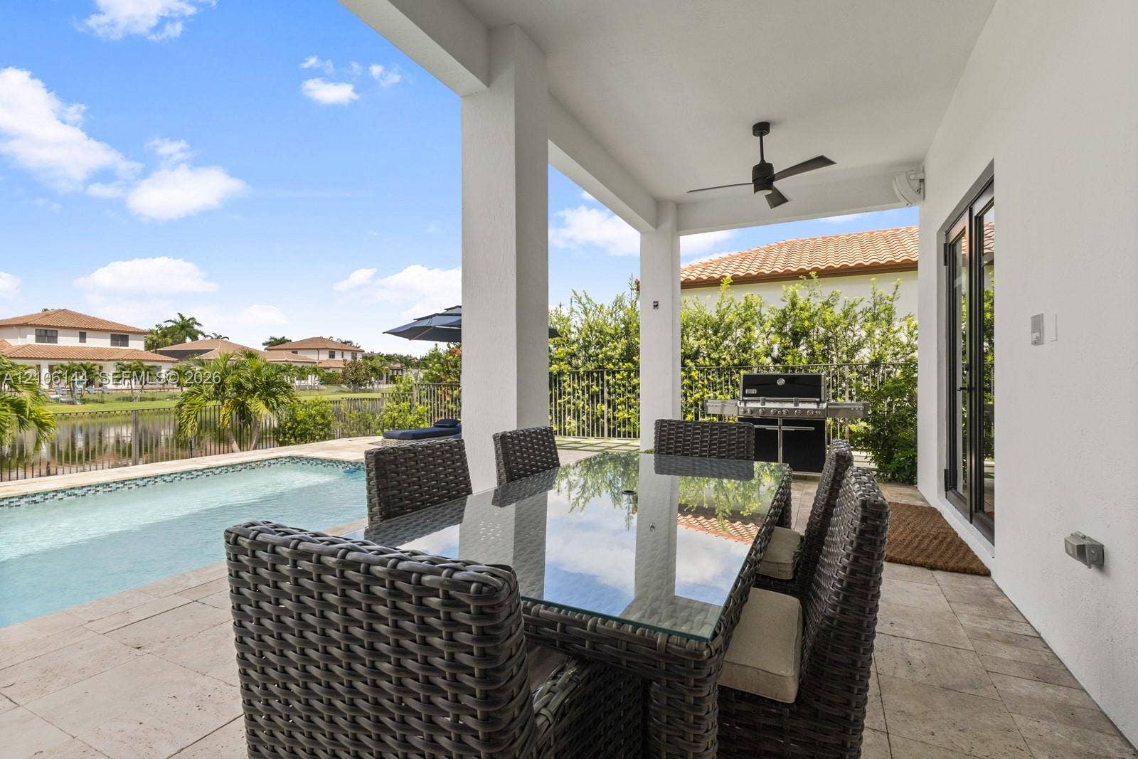 Covered patio featuring stone-tile flooring, a ceiling fan, and access to a swimming pool