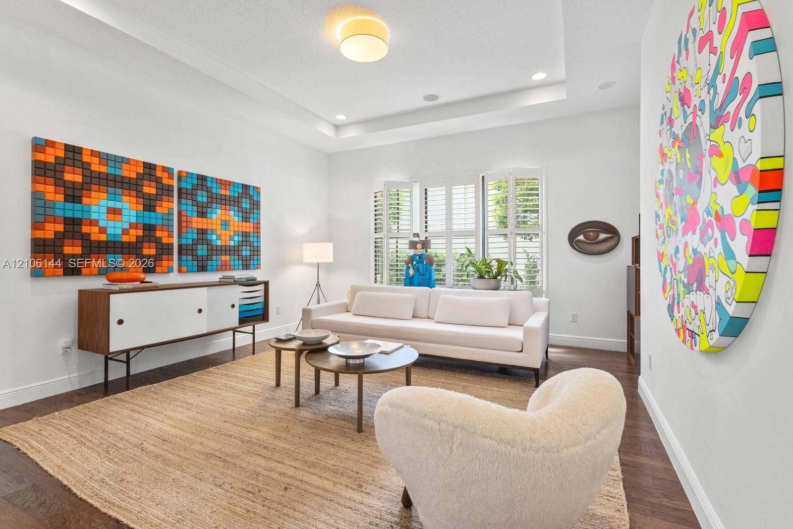 Living area featuring a tray ceiling, recessed lighting, wood-finish flooring, and white plantation shutters