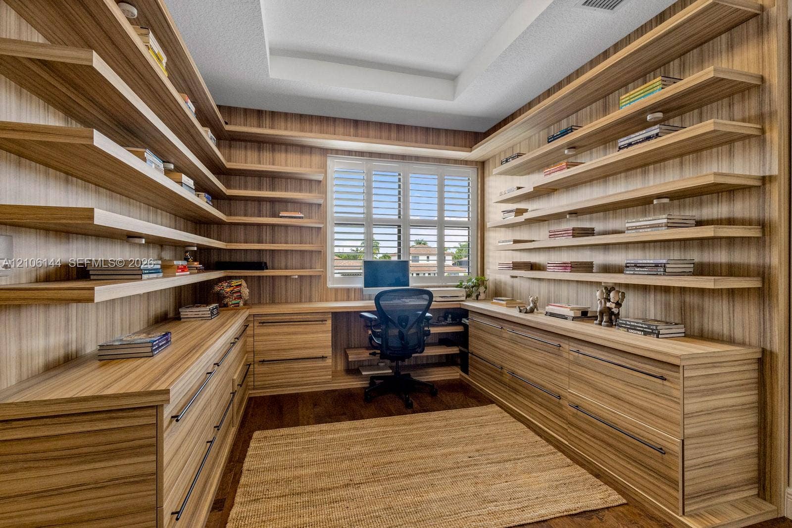 Custom-built wood-veneer cabinetry with extensive integrated shelving, deep-drawer storage, a coordinated built-in desk, and plantation shutters