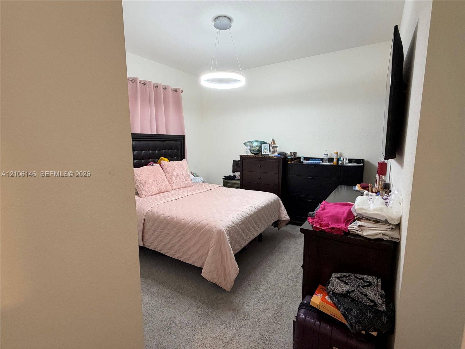 3259 W 100th Terrace, Hialeah, FL 33018 Neutral-toned carpeting, minimalist circular LED pendant light, and wall-mounted television