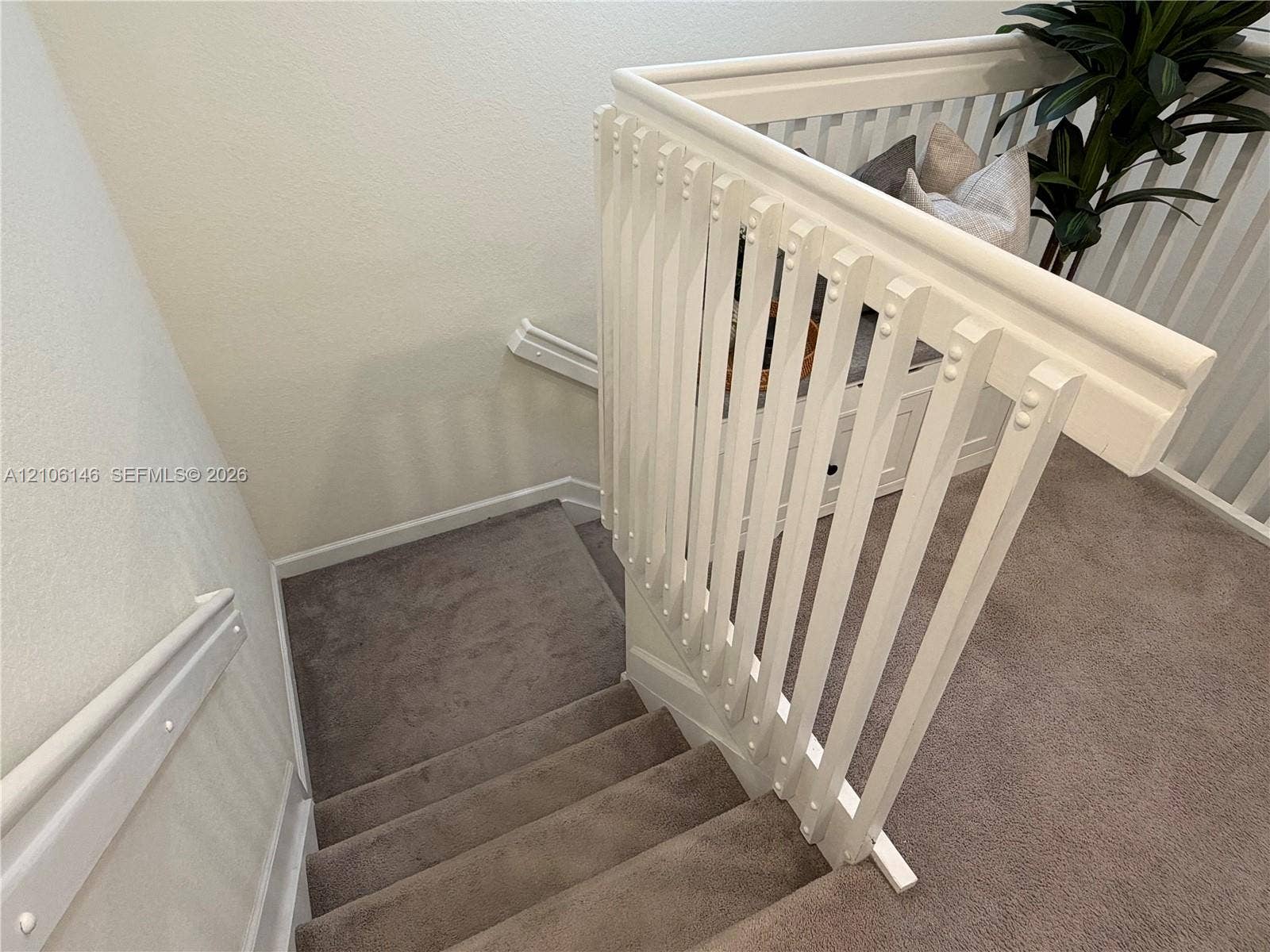 3259 W 100th Terrace, Hialeah, FL 33018 Staircase featuring neutral-toned carpeting, white painted wooden balusters, a matching handrail, and built-in storage cabinetry