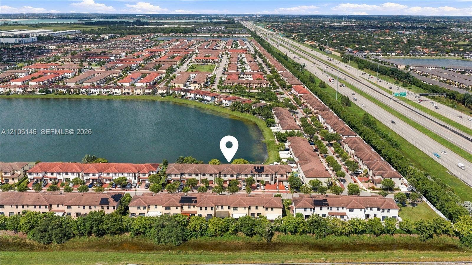 3259 W 100th Terrace, Hialeah, FL 33018 Aerial perspective of a multi-unit residential community situated along a waterfront with tile roofing and established perimeter landscaping