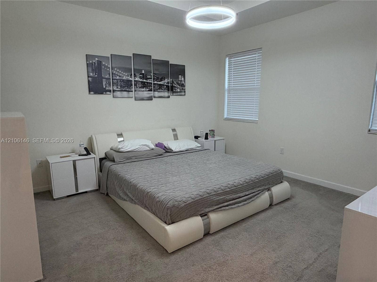 3259 W 100th Terrace, Hialeah, FL 33018 Tray ceiling featuring a contemporary circular LED light fixture, carpeted flooring, and windows with horizontal blinds