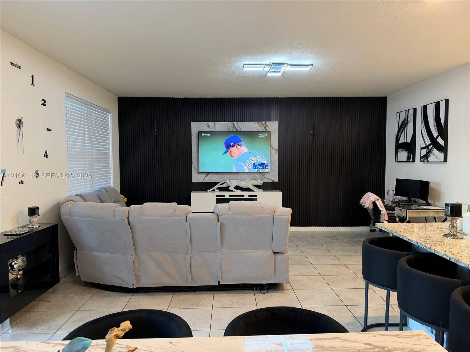 3259 W 100th Terrace, Hialeah, FL 33018 Accent wall featuring floor-to-ceiling vertical slats, stone-finish focal panel, large-format tile flooring, and integrated flush-mount ceiling lighting