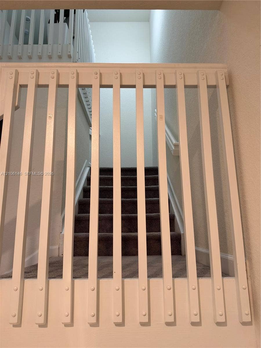3259 W 100th Terrace, Hialeah, FL 33018 White wooden vertical baluster gate with recessed hardware and carpeted stairway