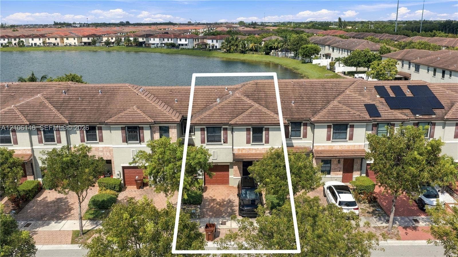 3259 W 100th Terrace, Hialeah, FL 33018 Waterfront townhouse exterior featuring a tiled roof, paver driveway, single-car garage, and stucco facade