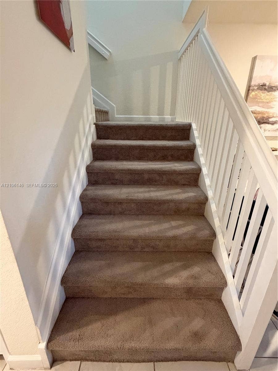 3259 W 100th Terrace, Hialeah, FL 33018 Staircase featuring wall-to-wall carpeting, white wooden balusters, and a painted handrail