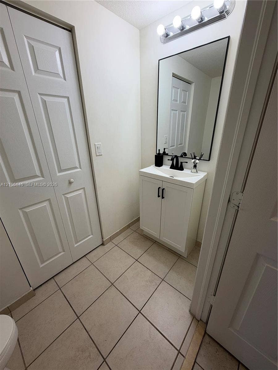 3259 W 100th Terrace, Hialeah, FL 33018 White vanity with a rectangular sink, matte black faucet, framed mirror, and tiled flooring