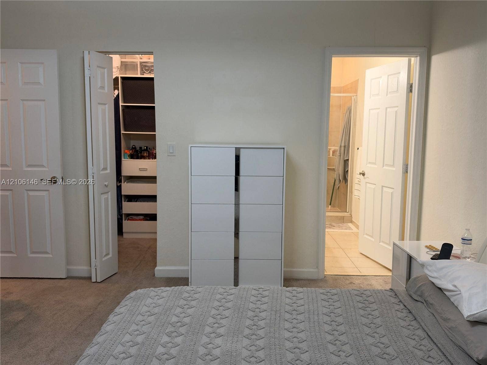 3259 W 100th Terrace, Hialeah, FL 33018 Room featuring neutral wall finishes and carpeted flooring, including a walk-in closet with built-in shelving, six-panel interior doors, and a separate room entry with tiled flooring