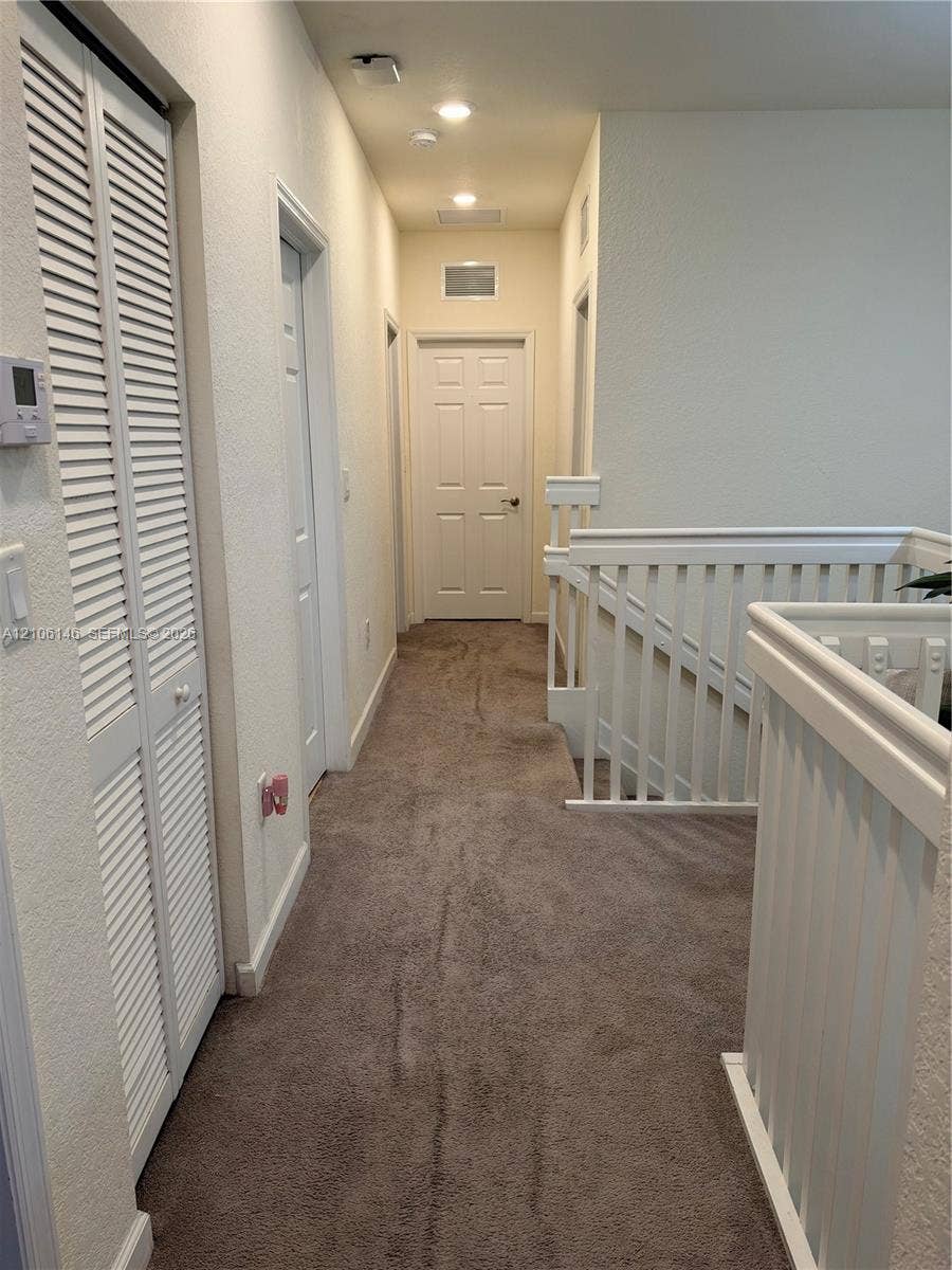3259 W 100th Terrace, Hialeah, FL 33018 Hallway featuring neutral wall-to-wall carpeting, white louvered-door closet, recessed ceiling lighting, and white wooden balustrade
