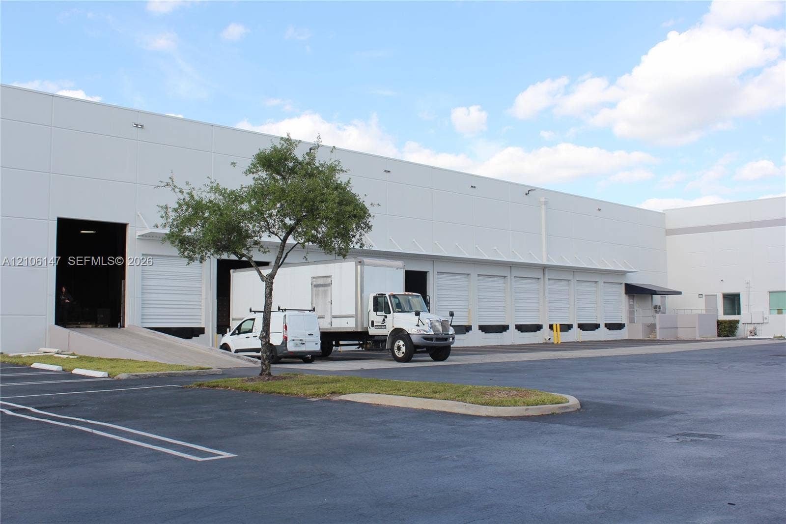 Industrial warehouse facility featuring a concrete tilt-wall exterior, multiple dock-high loading doors, and a dedicated concrete loading ramp