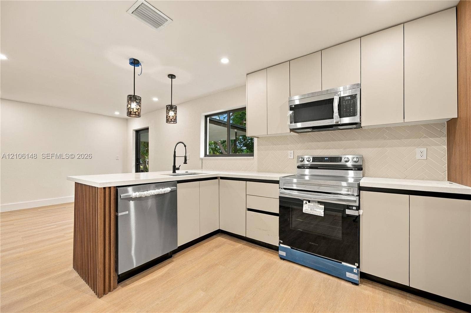 2920 Dorson Way, Delray Beach, FL 33445 Kitchen featuring flat-panel cabinetry, quartz countertops, herringbone-pattern backsplash, stainless steel appliances, and wood-finish flooring