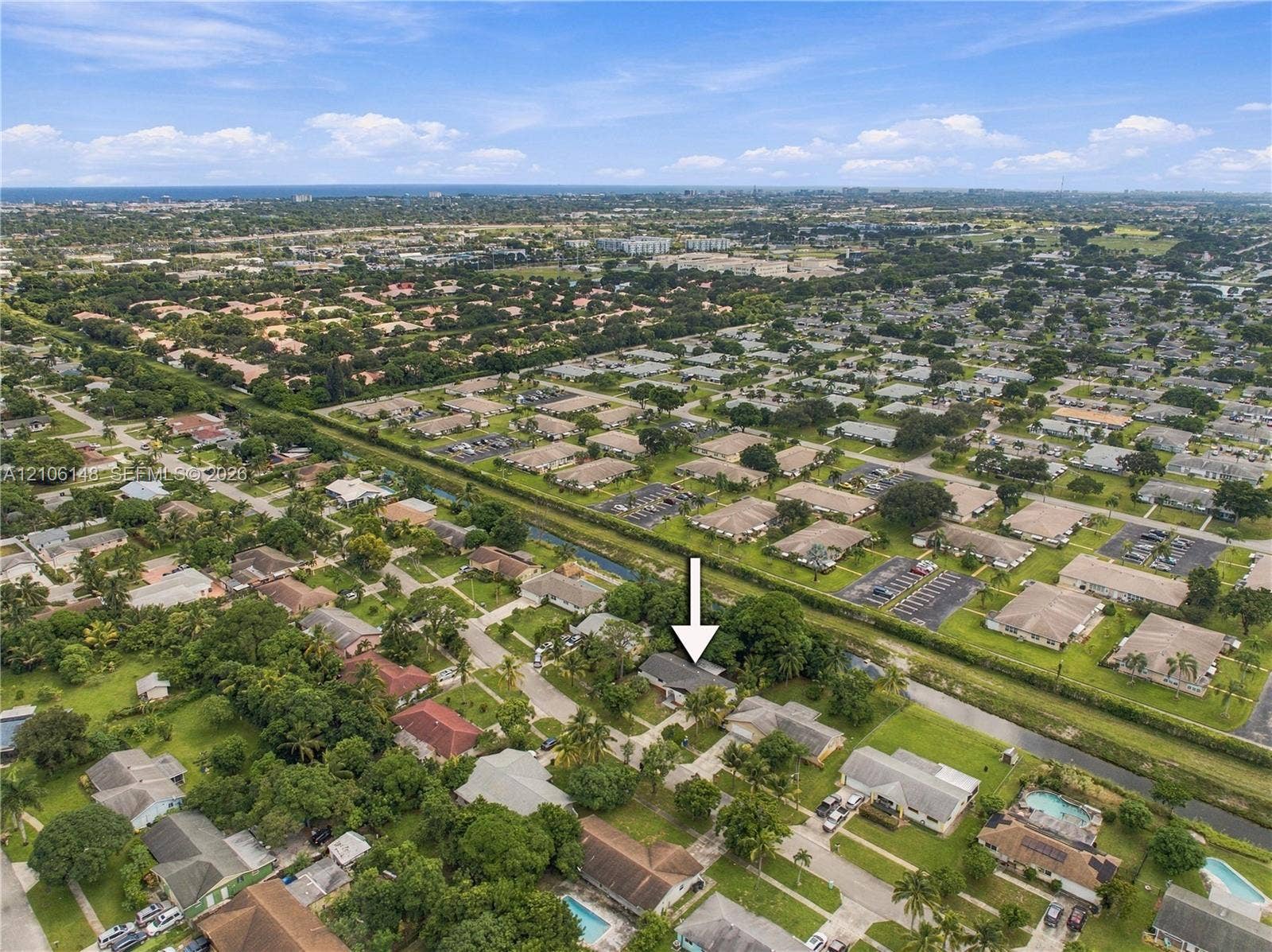 2920 Dorson Way, Delray Beach, FL 33445 Aerial perspective of a residential property featuring a pitched roof, attached garage, paved driveway, and mature landscaping within a suburban community