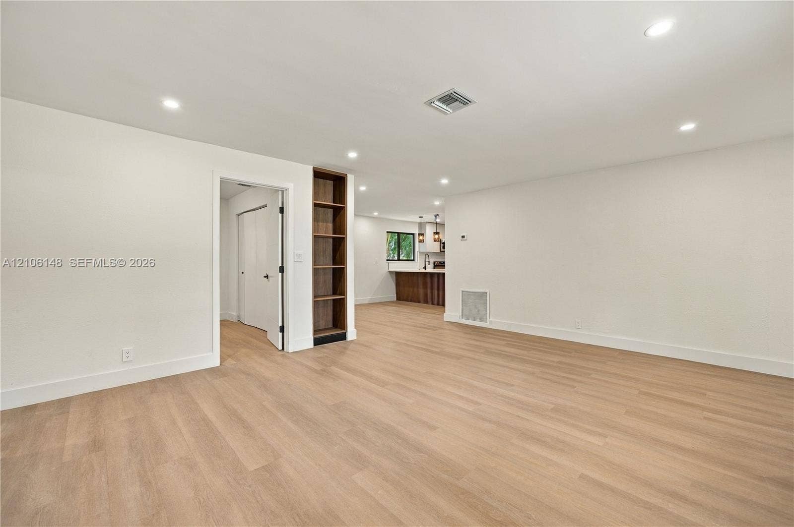 2920 Dorson Way, Delray Beach, FL 33445 Open-concept interior featuring light wood-finish flooring, recessed lighting, and a built-in floor-to-ceiling shelving unit