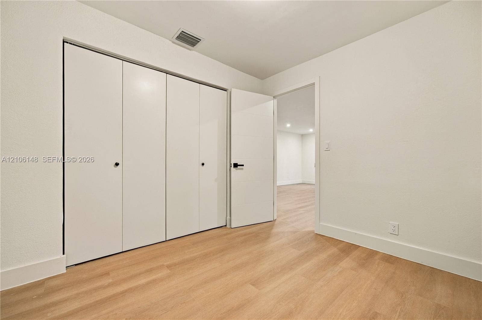 2920 Dorson Way, Delray Beach, FL 33445 Room featuring light-toned wood-finish flooring, white walls, and a multi-panel closet with matte black hardware