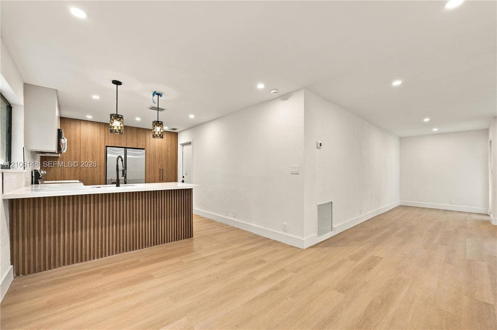 2920 Dorson Way, Delray Beach, FL 33445 Kitchen featuring wood-finish cabinetry, a ribbed kitchen island with a light stone countertop, recessed lighting, and wood-finish flooring