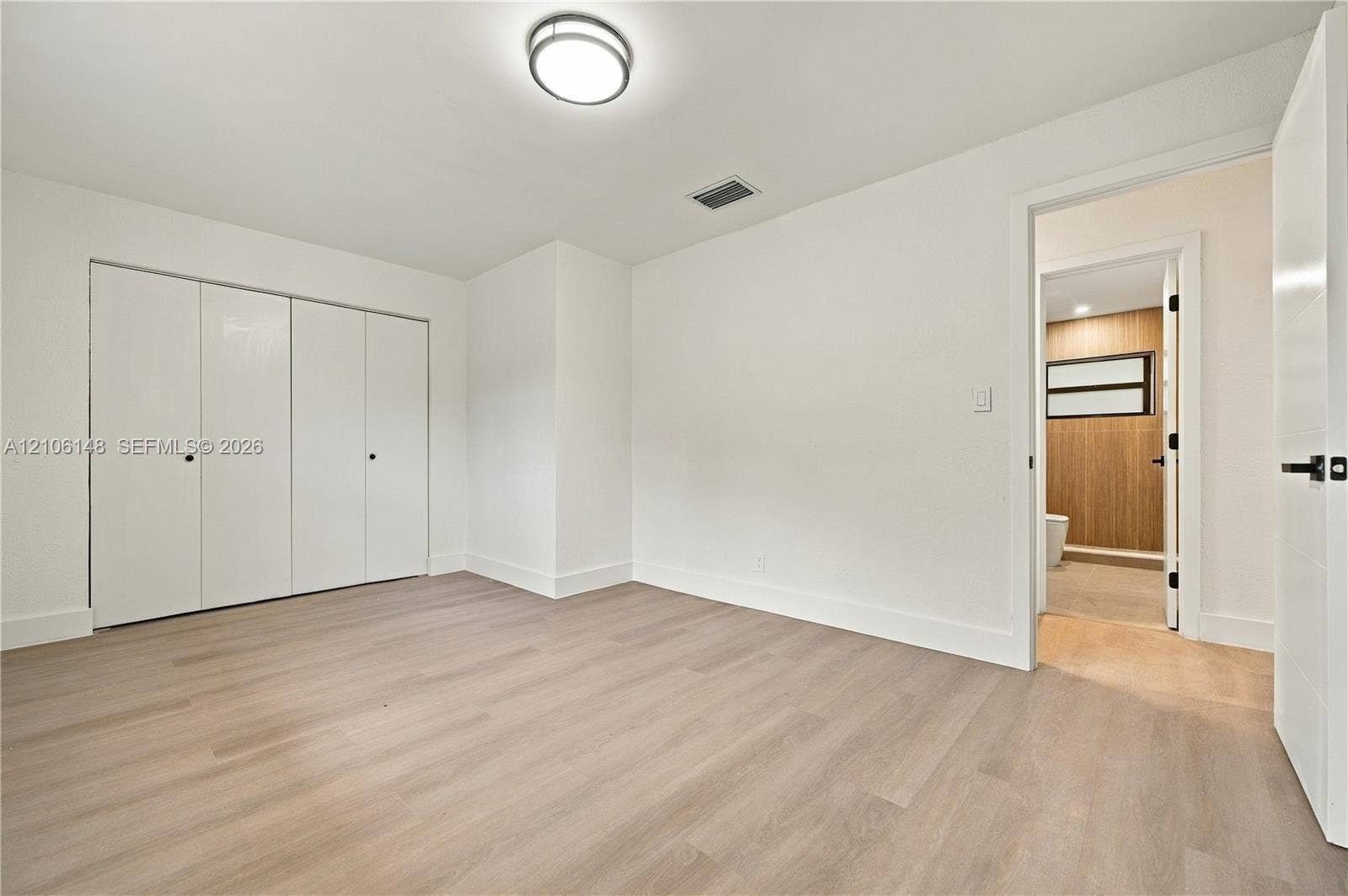 2920 Dorson Way, Delray Beach, FL 33445 Interior room featuring wood-finish flooring, white walls, flush-mount lighting, and floor-to-ceiling closets with double-door access