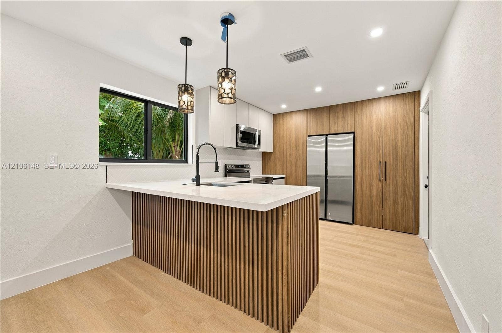 2920 Dorson Way, Delray Beach, FL 33445 Kitchen featuring a slatted wood-finish island with a quartz countertop, matte black faucet, custom floor-to-ceiling wood cabinetry, and recessed lighting