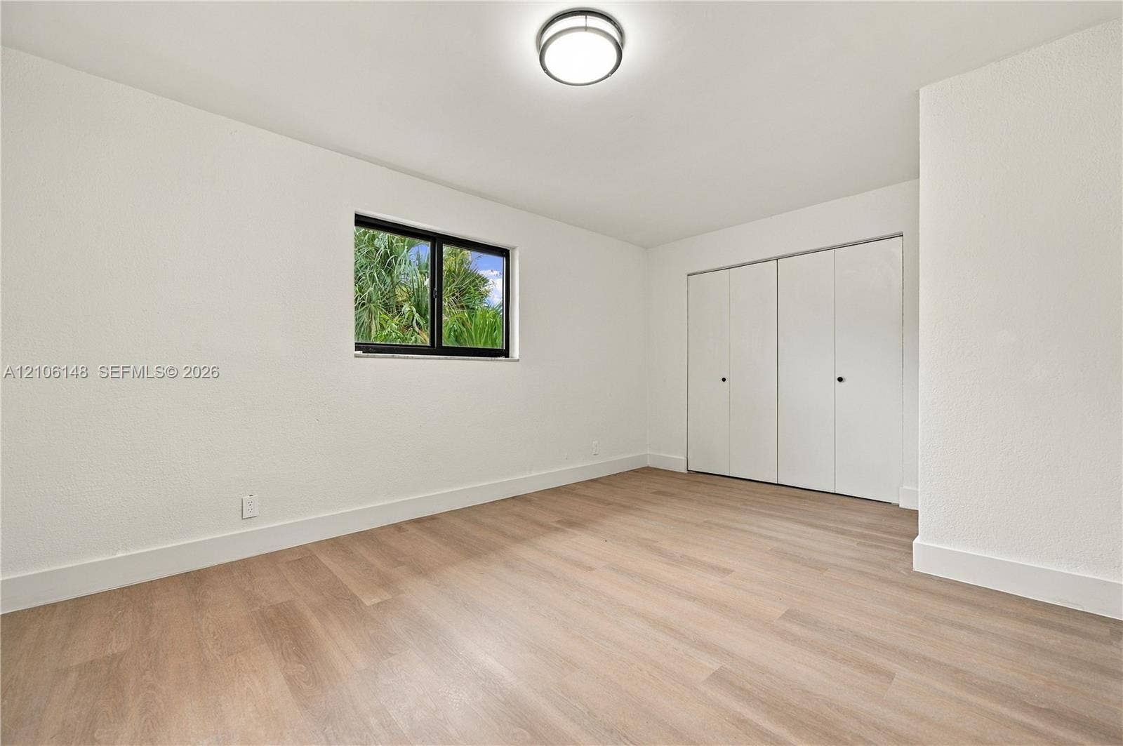 2920 Dorson Way, Delray Beach, FL 33445 Neutral-toned wood-finish flooring, white walls, dual-panel closet doors, single-hung window with black frame, and flush-mount ceiling lighting
