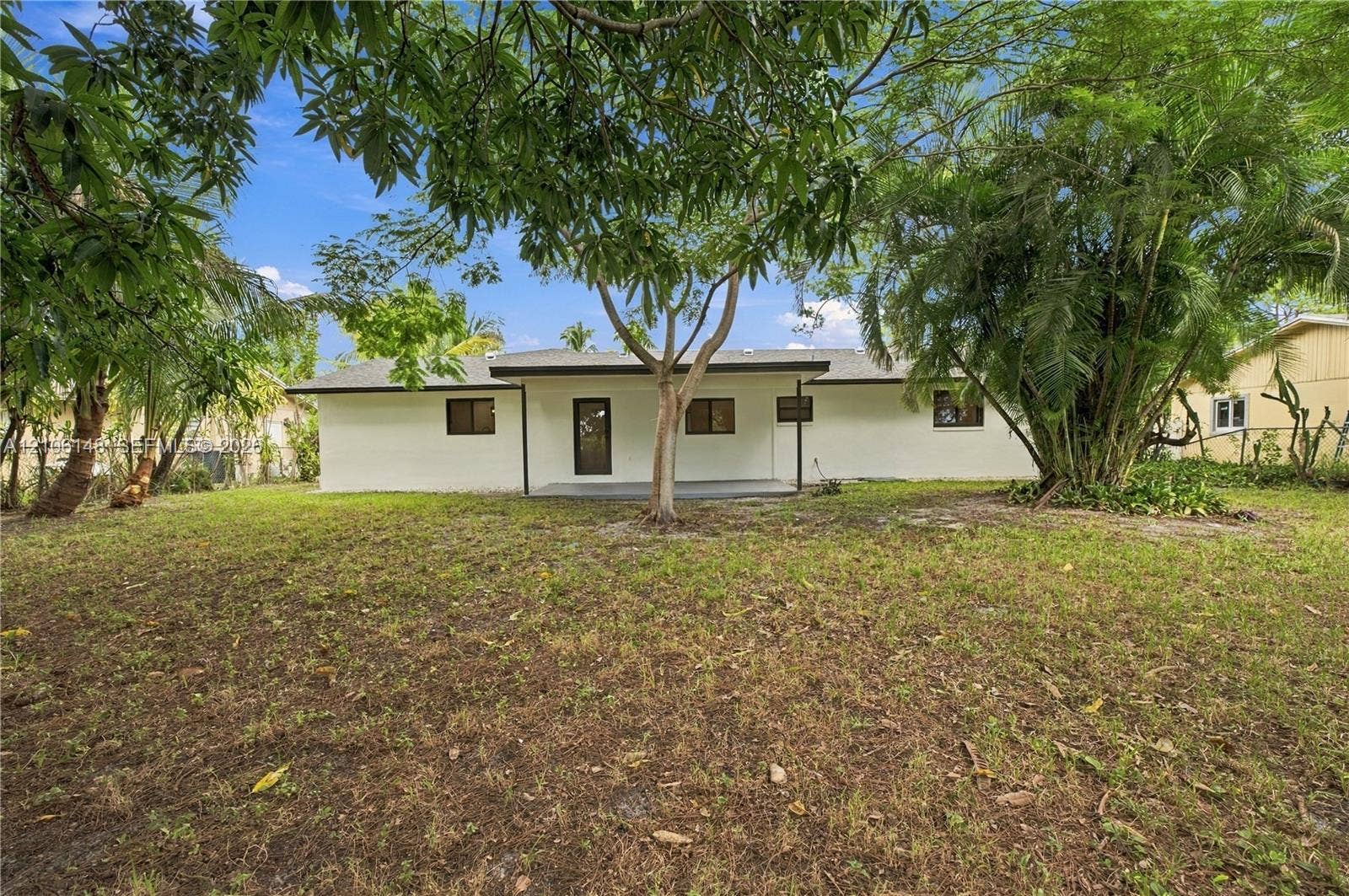 2920 Dorson Way, Delray Beach, FL 33445 Single-story residence featuring a smooth stucco exterior, a covered rear patio, and mature landscaping