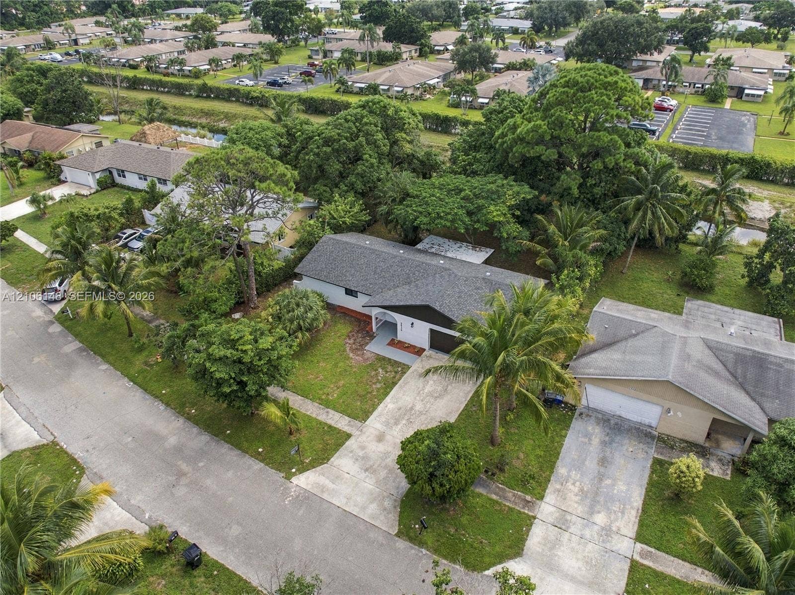 2920 Dorson Way, Delray Beach, FL 33445 Aerial perspective of a single-story residence featuring a composite shingle roof, a concrete driveway, and mature landscaping