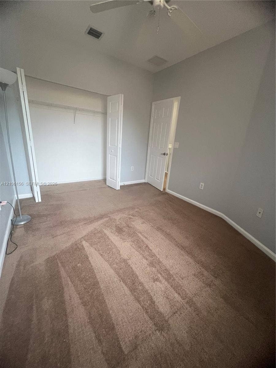 Carpeted interior space featuring a ceiling fan, closet with bi-fold doors, and a paneled interior door