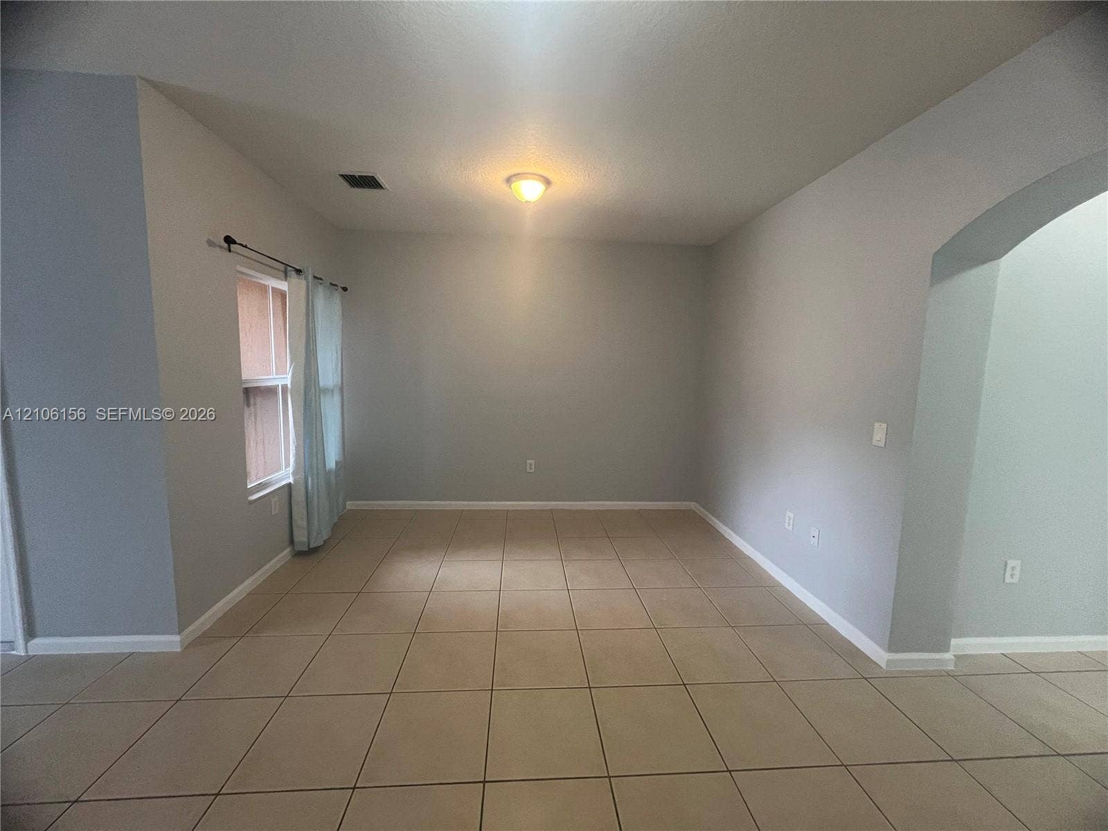 Interior space featuring neutral wall paint, large format tile flooring, a recessed archway, and a flush-mount light fixture