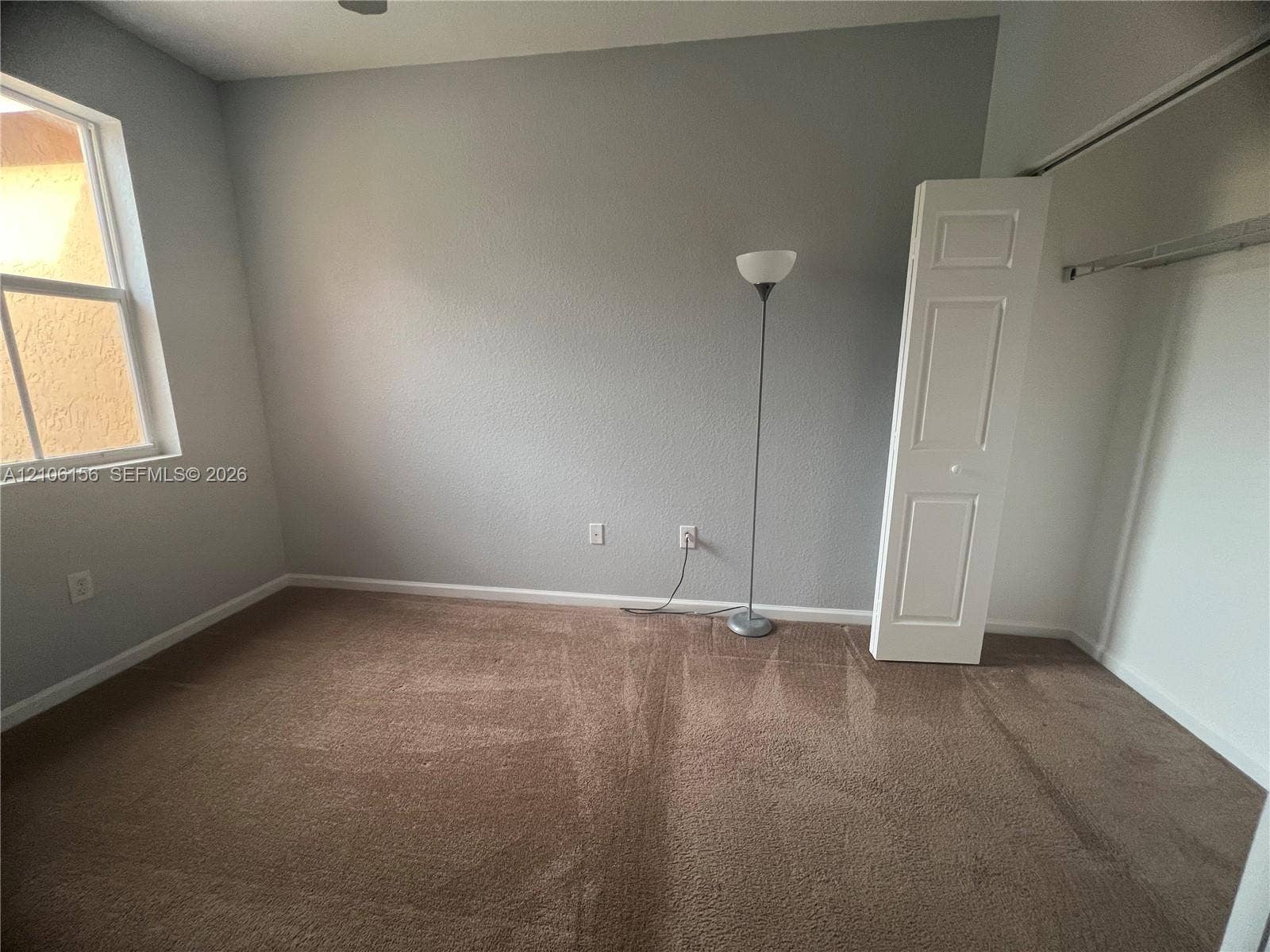 Neutral-toned interior featuring wall-to-wall carpeting, a multi-pane window, and a built-in closet with folding doors