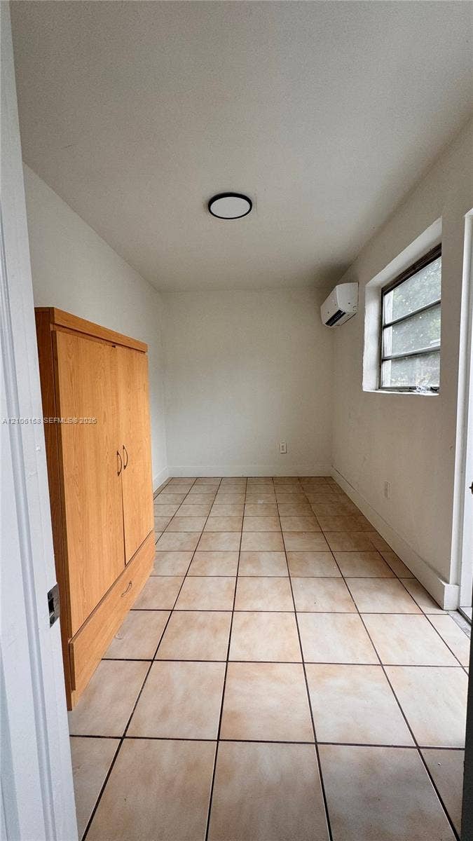 Square ceramic floor tiling, wall-mounted ductless air conditioning unit, recessed ceiling lighting, and horizontal window