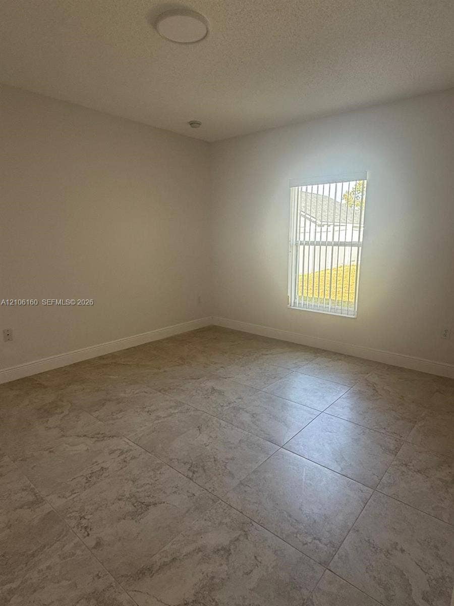 Neutral-toned tile flooring, recessed ceiling lighting, and vertical window blinds