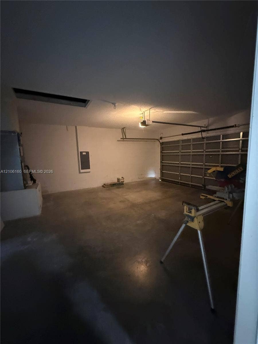Enclosed garage featuring a concrete floor, overhead door, and ceiling-mounted garage door opener