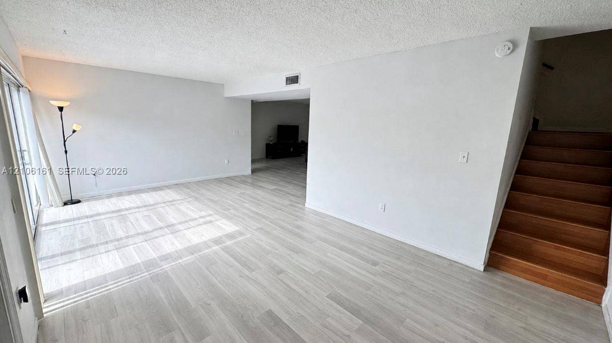 15460 SW 82nd Lane, #403, Miami, Miami, FL 33193 Open-concept floor plan featuring wood-finish flooring, staircase with wood treads, and sliding glass door