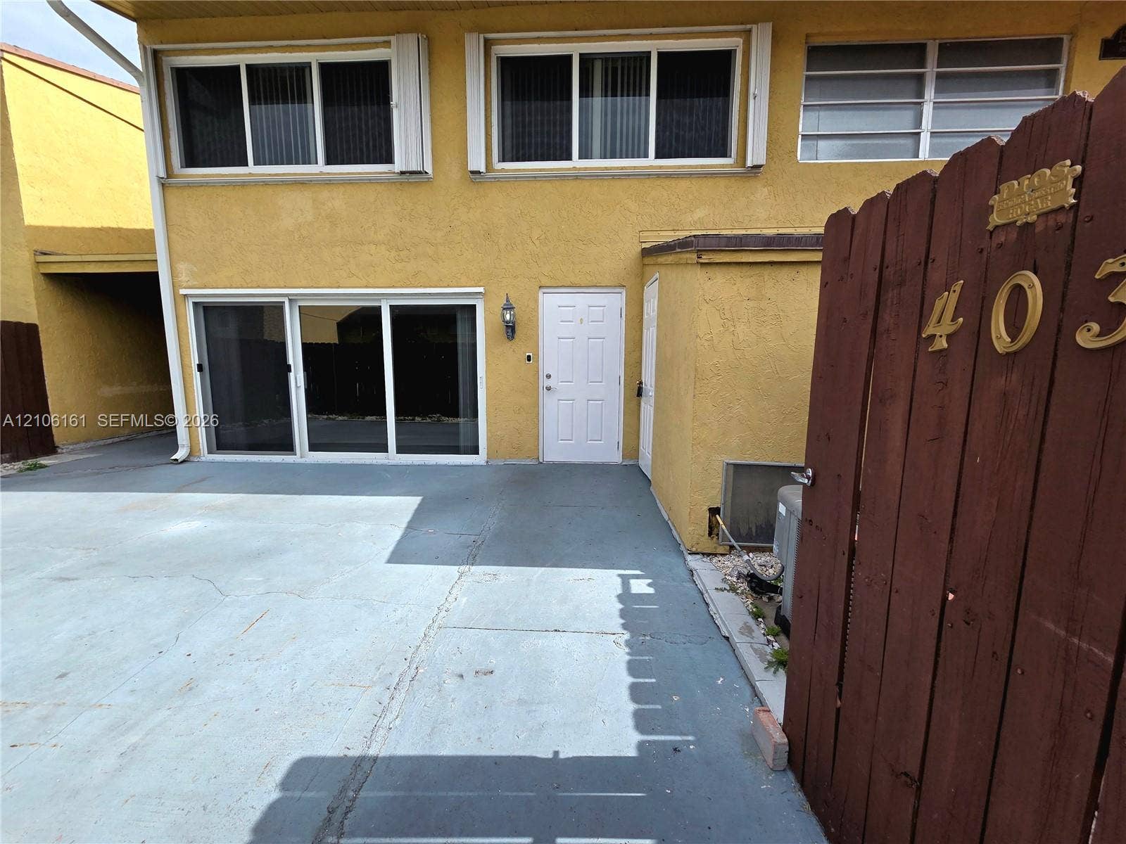 15460 SW 82nd Lane, #403, Miami, Miami, FL 33193 Multi-level exterior featuring a smooth stucco finish, sliding glass patio doors, panel-style entry door, horizontal sliding windows, and a dedicated concrete courtyard