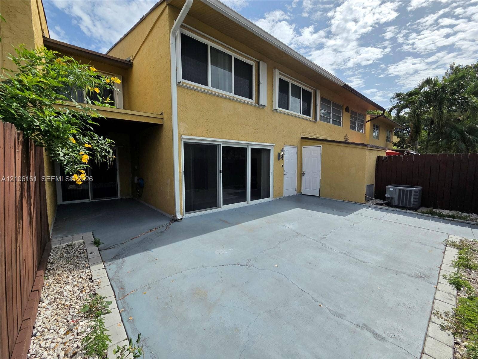 15460 SW 82nd Lane, #403, Miami, Miami, FL 33193 Two-story stucco exterior featuring a large concrete patio, sliding glass doors, and a wood privacy fence