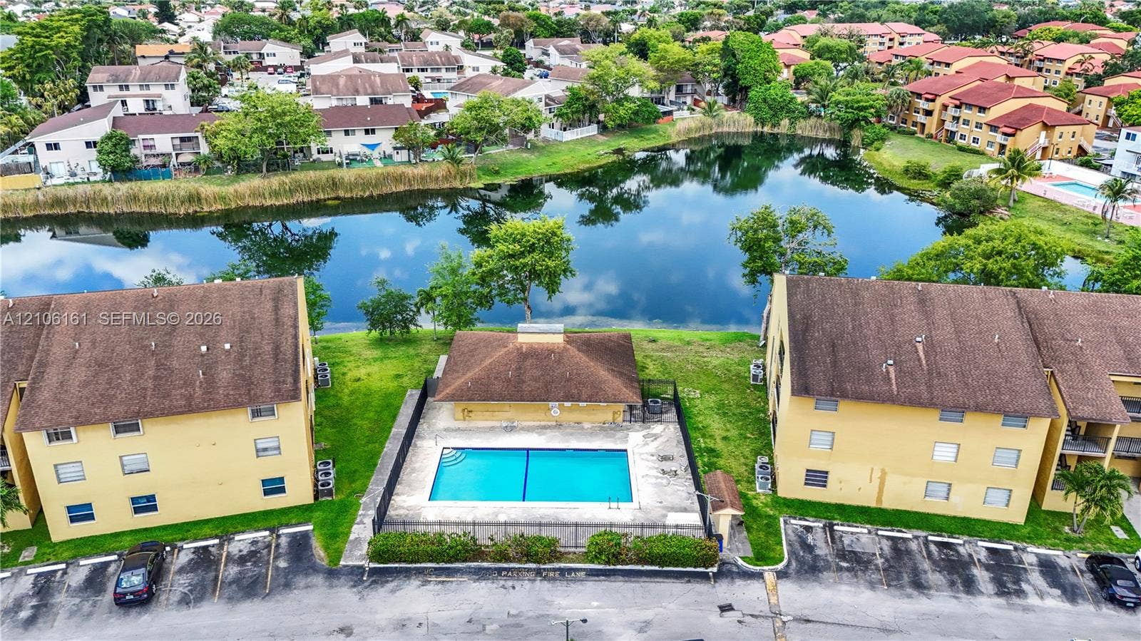 15460 SW 82nd Lane, #403, Miami, Miami, FL 33193 Aerial perspective featuring a swimming pool, surrounding concrete deck, black perimeter fencing, and water frontage